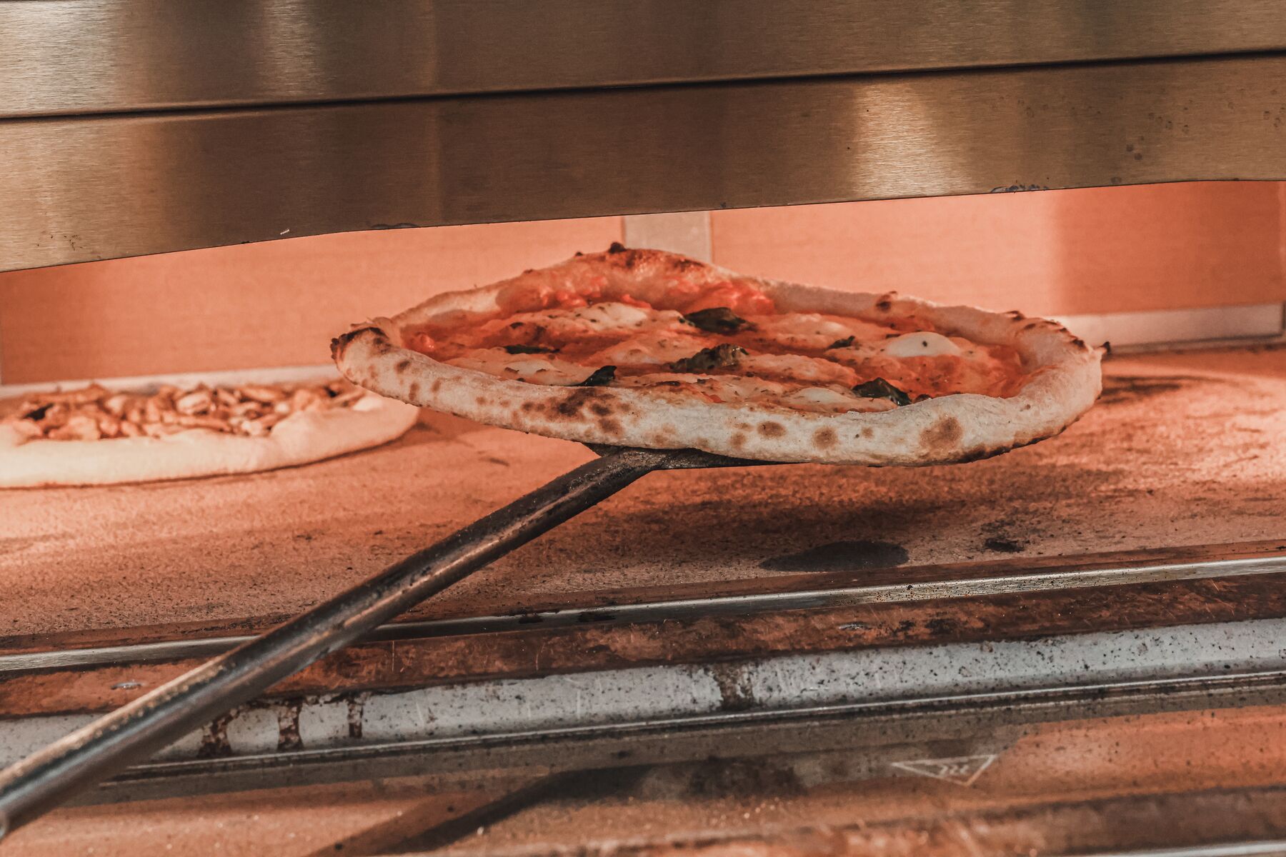 Une pizza margherita sortie du four à pierre sur la pelle du pizzaïolo