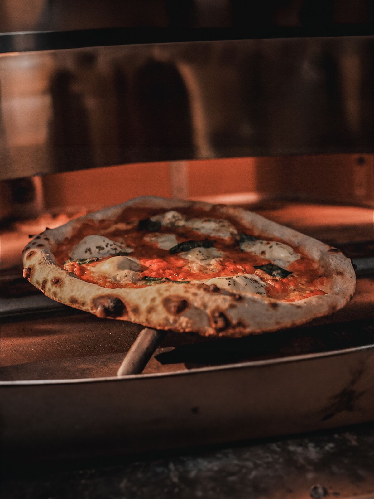 Pizza margherita en cuisson dans le four à pierre