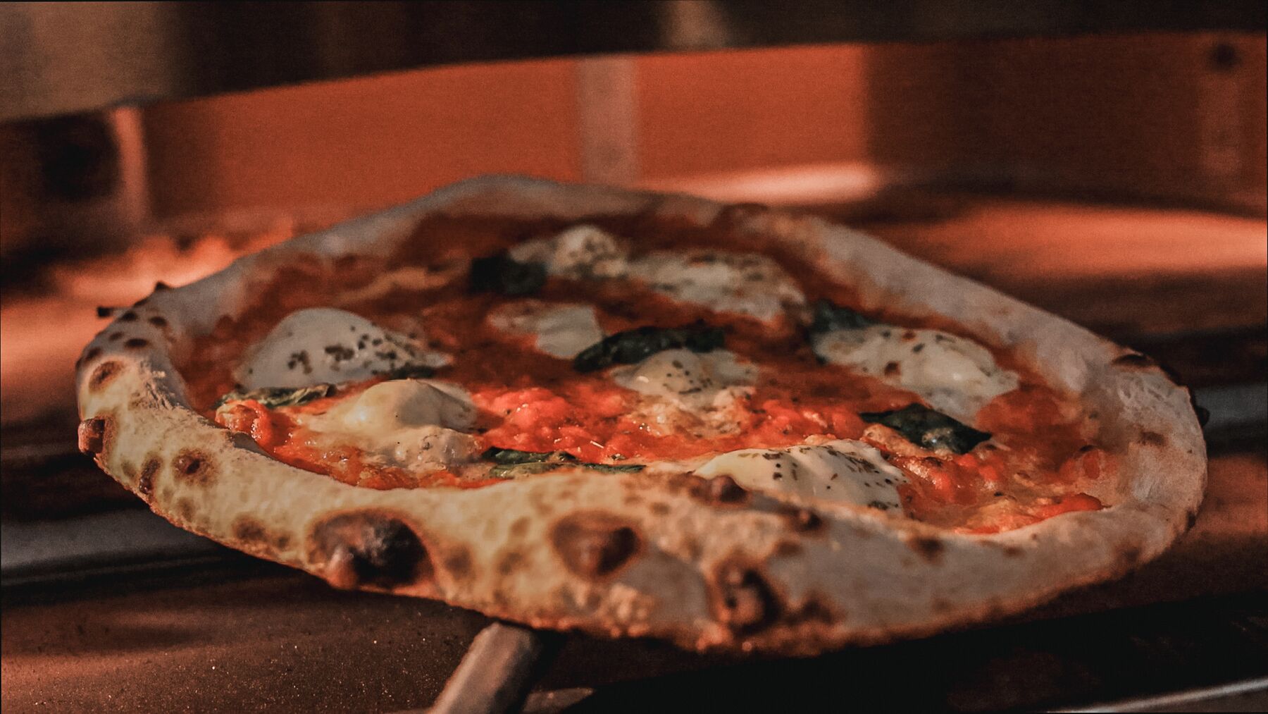 Pizza en fin de cuisson devant la flamme du four